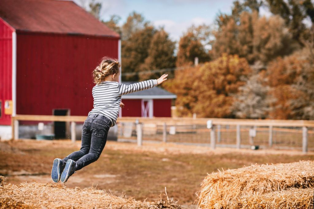 Girl Jumping in hay at fall festival